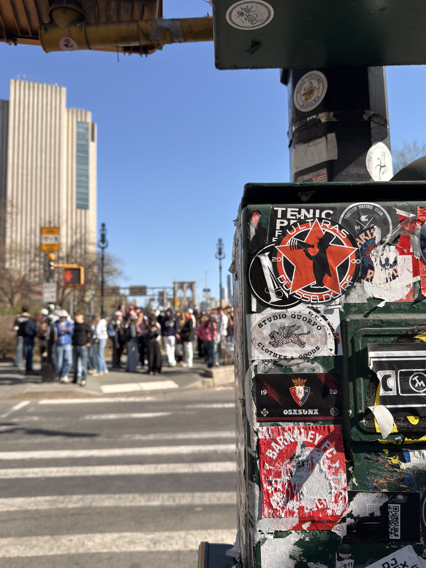 The central sticker is a circular design, primarily red and black. It features a prominent red five-pointed star in the center. Overlaid on the star is a black silhouette of a figure, resembling a man in a top hat or bowler hat, holding a megaphone to his mouth. Encircling the red star is a black band with white text. The word 'ULTRAS' is written in capital letters along the top curve of this band, and 'DÜSSELDORF' is written along the bottom curve. To the left side of the black band, the letter 'M' is visible in white, and to the right, the number '20' is visible in white, both integrated into the circular design.
