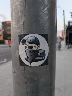 Square sticker with a circular grayscale graphic of a man wearing a cap, sunglasses, and a face bandana. The text 'ANTONIO 21' is on his collar.
