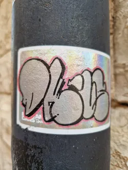 A holographic sticker with grey graffiti art. The sticker has a pink outline and the text "LARSAN" is visible in the bottom left corner. 