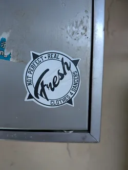 Street sticker Circular black and white sticker with a compass star background. Features stylized 'Fresh' script in the center, surrounded by the text 'NOT PERFECT • REAL' and 'CLOTHES 4 DANCERS'.