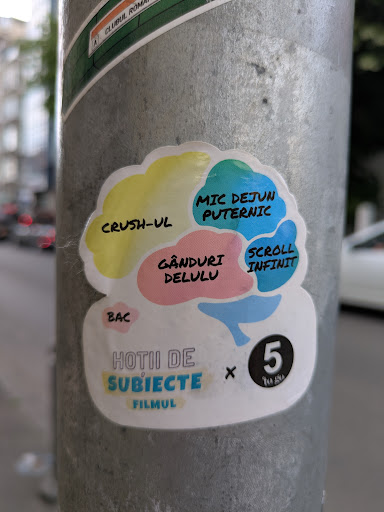 This sticker features a stylized brain illustration, with different sections labeled with thoughts and activities. The upper sections include "Crush-UL", "Mic Dejun Puternic" (Powerful Breakfast), and "Scroll Infinit" (Infinite Scroll). The lower section is labeled "Hotii de Subiecte Filmul" (Movie Subject Thieves) and includes a logo for "5 Tea Asia."