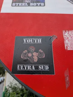 A square black sticker depicting a muscular, red-haired character flexing his biceps. The text 'YOUTH' is printed above in a distressed white font, and 'ULTRA SUD' is printed below in the same style.