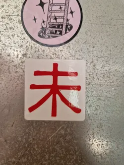 Street sticker This sticker showcases a single, bold red Chinese character, 未来 (wèilái), meaning "future," printed on a white square background.  The character is stylized with thick strokes and is the primary focus of the design.  It's a minimalist design that packs a powerful message.