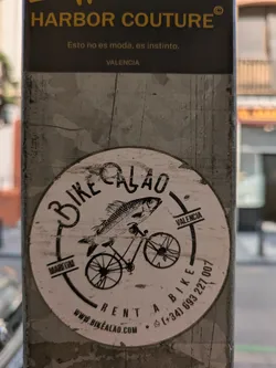 Street sticker A round sticker featuring a fish riding a bicycle. The text indicates it's a bike rental service in Valencia.