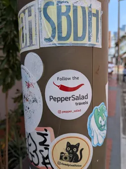 Street sticker A circular white sticker featuring a red chili pepper graphic. Text reads 'Follow the PepperSalad travels' with an Instagram handle '@pepper_salad' at the bottom.
