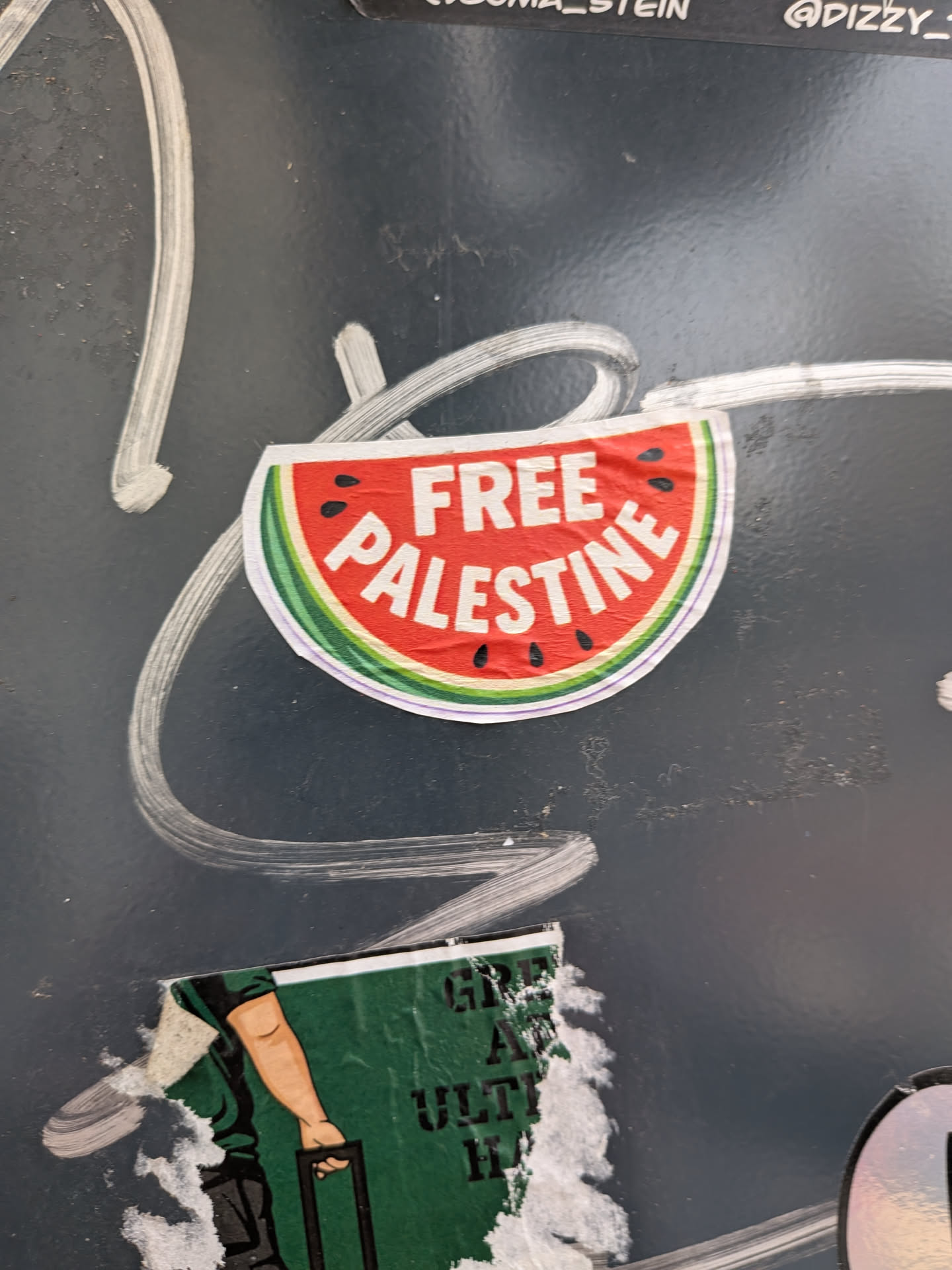 A semi-circular sticker designed as a watermelon slice with a red center, black seeds, and a green rind. The bold white text 'FREE PALESTINE' is printed across the red section.