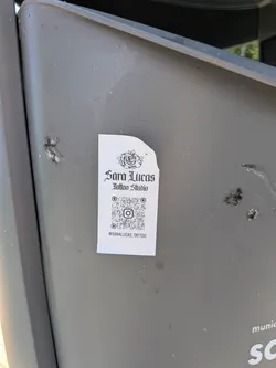 Street sticker A rectangular white sticker featuring a black rose illustration, gothic-style text reading 'Sara Lucas Tattoo Studio', a central QR code with an Instagram logo, and the handle '@SARALUCAS_TATTOO' at the bottom.