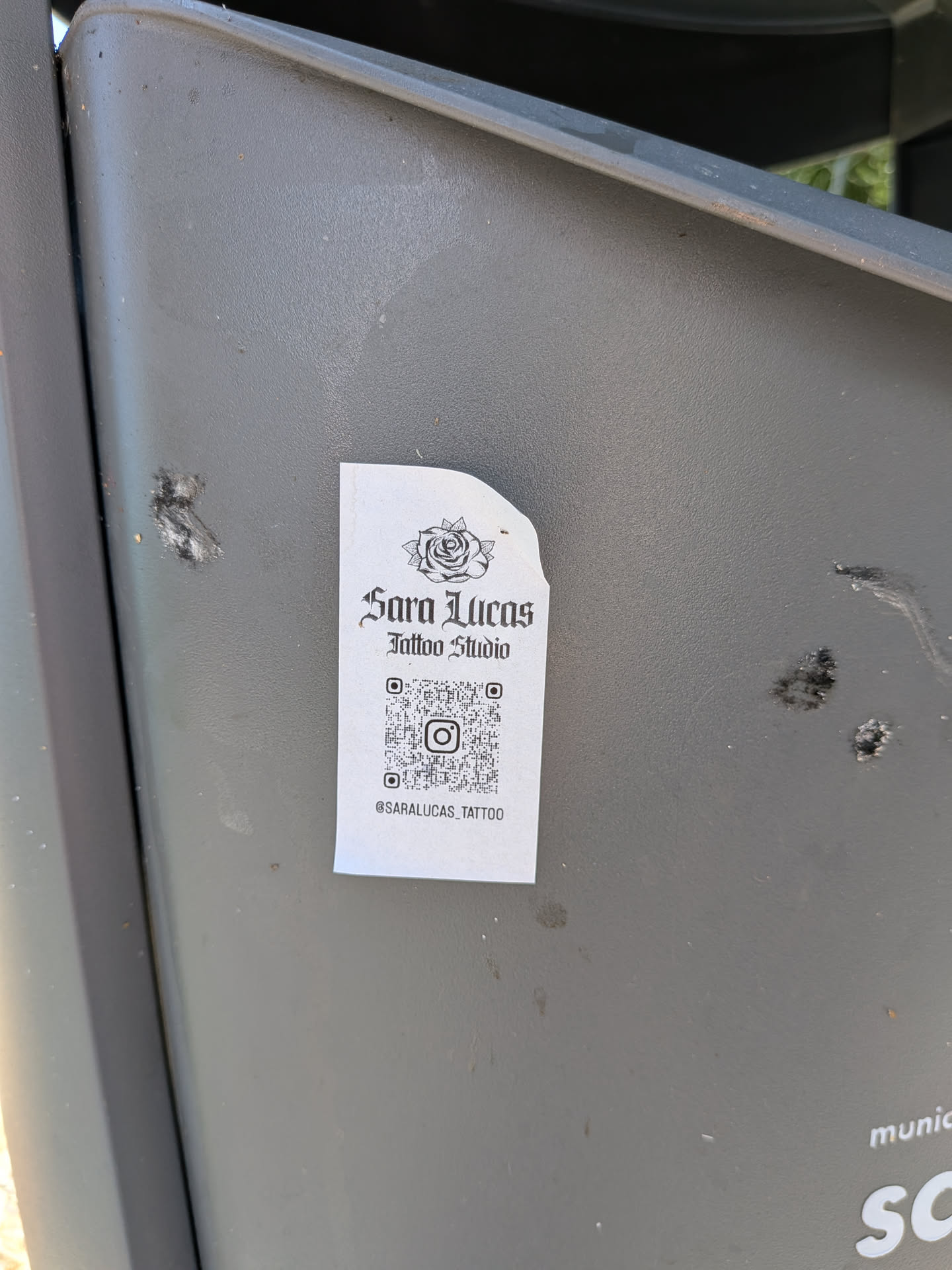 A rectangular white sticker featuring a black rose illustration, gothic-style text reading 'Sara Lucas Tattoo Studio', a central QR code with an Instagram logo, and the handle '@SARALUCAS_TATTOO' at the bottom.