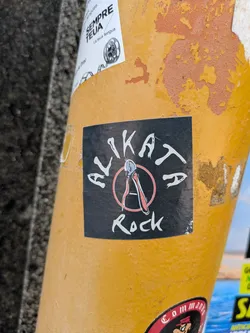 Street sticker A black and white sticker of Alikat Rock. The sticker features a logo with a pair of wire cutters in the center of a red circle. The words Alikat Rock are printed around the logo.