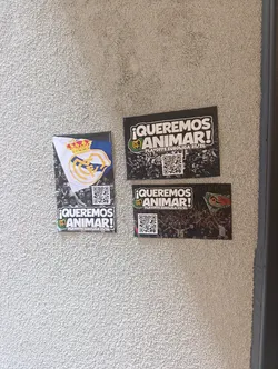 Street sticker A horizontally oriented rectangular sticker with a dark, abstract background resembling shattered glass or a digital effect. The top section features bold white text '¡QUEREMOS ANIMAR!' (We Want to Cheer!) with a green outline, and below it, 'PLAYOFFS EUROLIGA 23/26' in smaller white text. A small Real Madrid crest, featuring a crown and the 'RM' monogram, is visible to the left of the main text. In the bottom center, a black and white QR code is prominently displayed against the dark background.