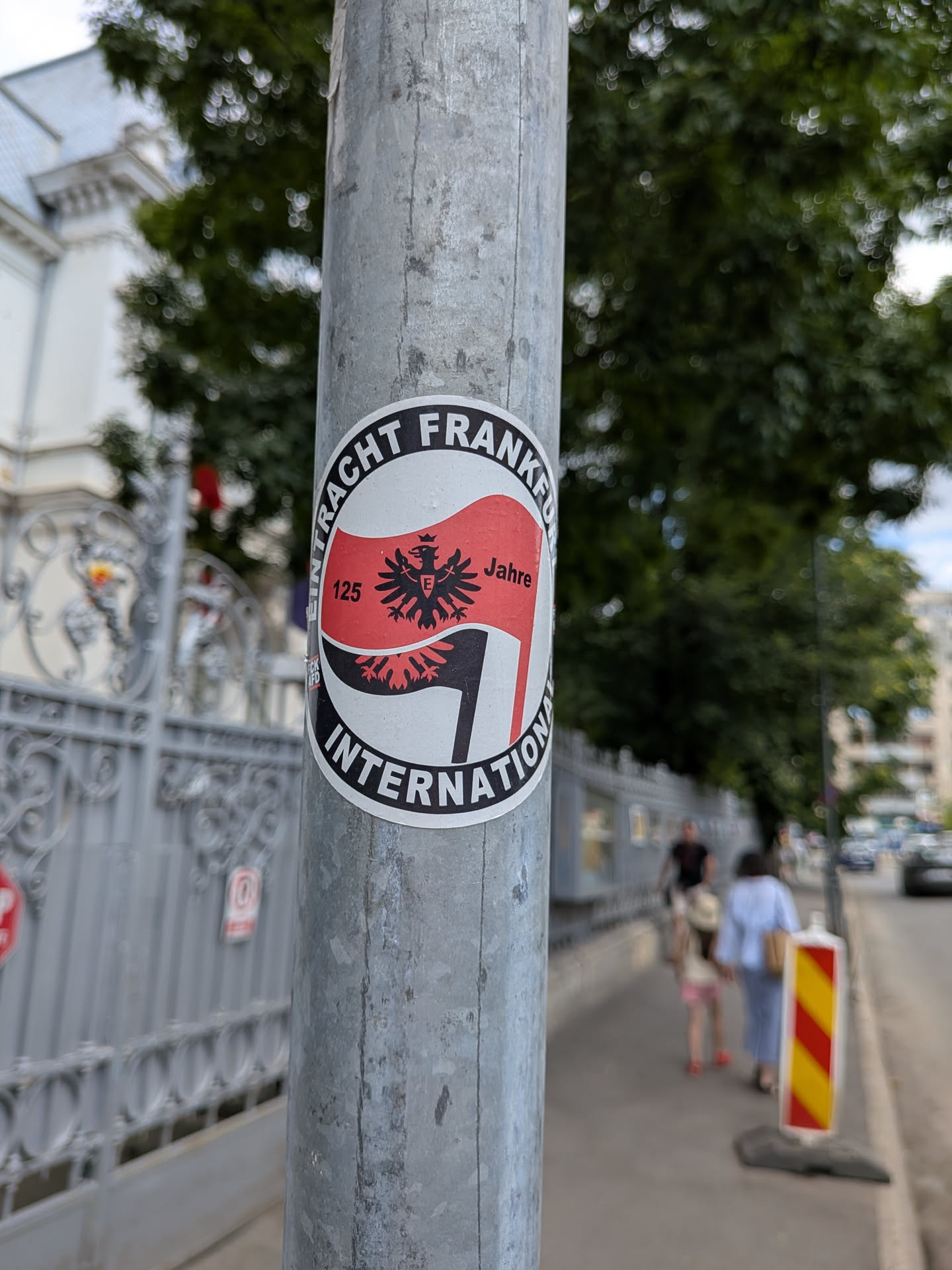 Circular sticker with a black border reading 'EINTRACHT FRANKFURT INTERNATIONAL'. The center features a red and black waving flag with the club's eagle crest and '125 Jahre' text.