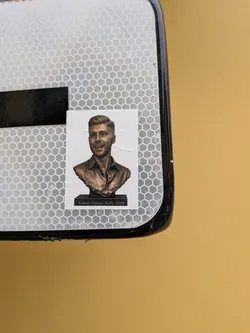 Street sticker A rectangular white sticker featuring a bronze-colored bust of a smiling man with styled hair and a collared shirt. The bust rests on a black base inscribed with the text 'Tomás Farias, Rally 2026'.