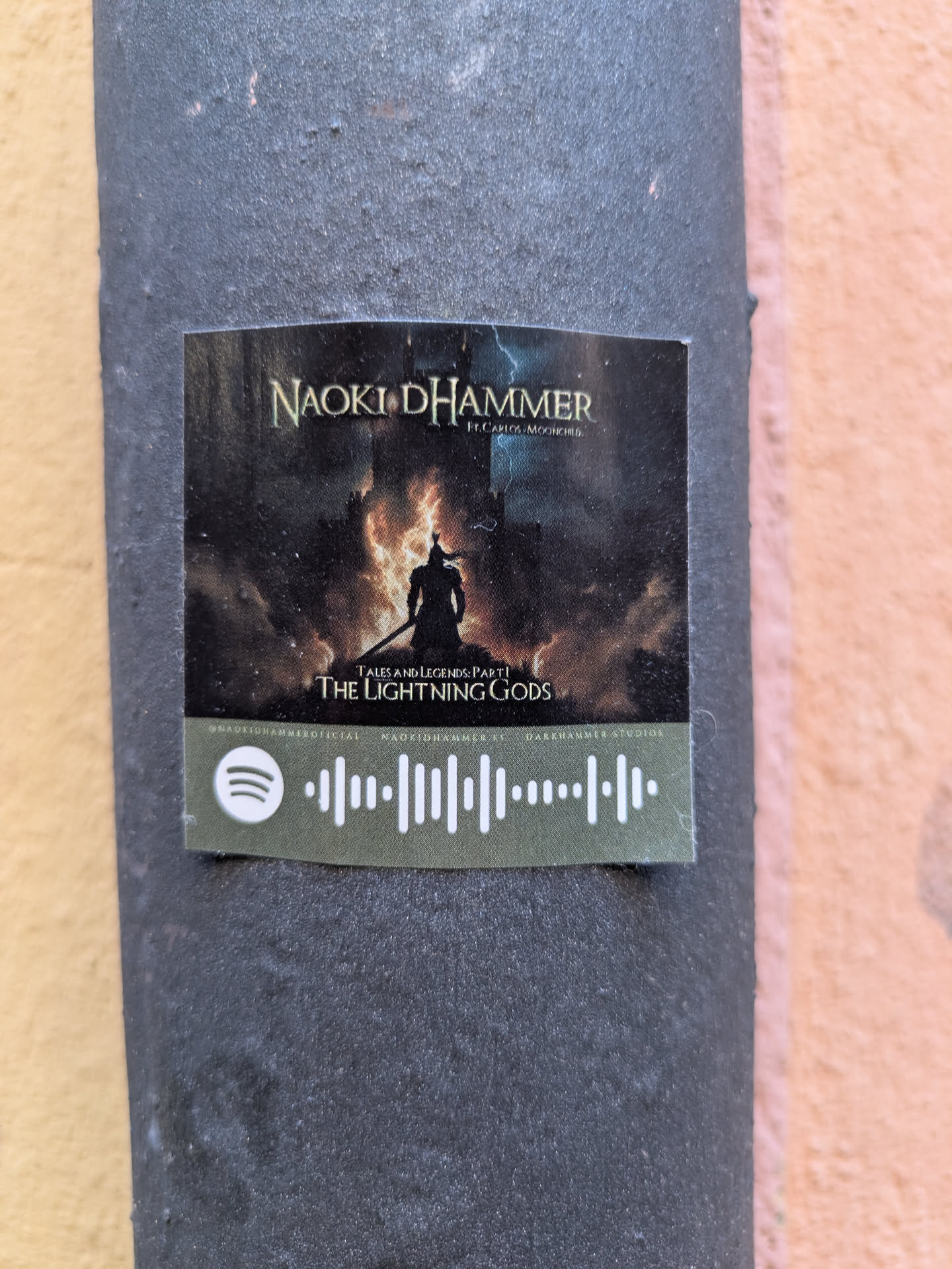 A sticker for the music artist Naoki D'Hammer featuring the song "The Lightning Gods" with Carlos Moonchild. The sticker also contains a Spotify code.