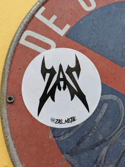 Street sticker This is a round sticker featuring the logo for the ZAS metal band. The logo is in a dark, jagged font. Below the logo is the Instagram handle @ZAS_METAL.