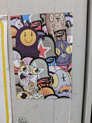 A sticker shows a compilation of colorful cartoon characters. It has multiple eyes, stars, smileys and other abstract shapes, creating a unique and eye-catching design.