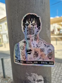 Street sticker This iridescent sticker showcases a stylized character adorned with a collection of tattoos across their chest and shoulders.  Their face is obscured by a QR code. The sticker has a holographic or iridescent finish. The bottom of the sticker includes the Instagram handle @kla_ink repeated three times.