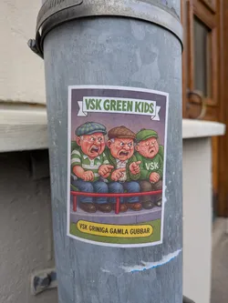 Street sticker The sticker features a cartoon illustration of three elderly men with exaggeratedly angry and grumpy expressions. They are seated on a red railing, wearing flat caps and striped shirts. The man on the left wears a green and white striped shirt and a green checkered cap. The middle man wears a white shirt with green stripes and a brown cap. The man on the right wears a green sweater with 'VSK' printed on it and a green cap. The background is a muted purple banner with the text 'VSK GREEN KIDS' in green letters. Below the railing, a yellow oval contains the text 'VSK GRINIGA GAMLA GUBBAR'. The overall style is reminiscent of vintage comic art.