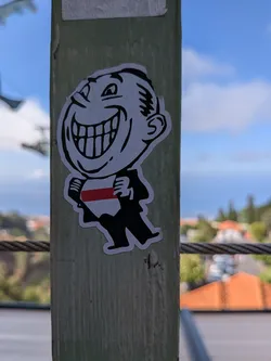 Street sticker Die-cut sticker of a grinning cartoon man in a suit pulling open his shirt to show a white-red-white striped flag.