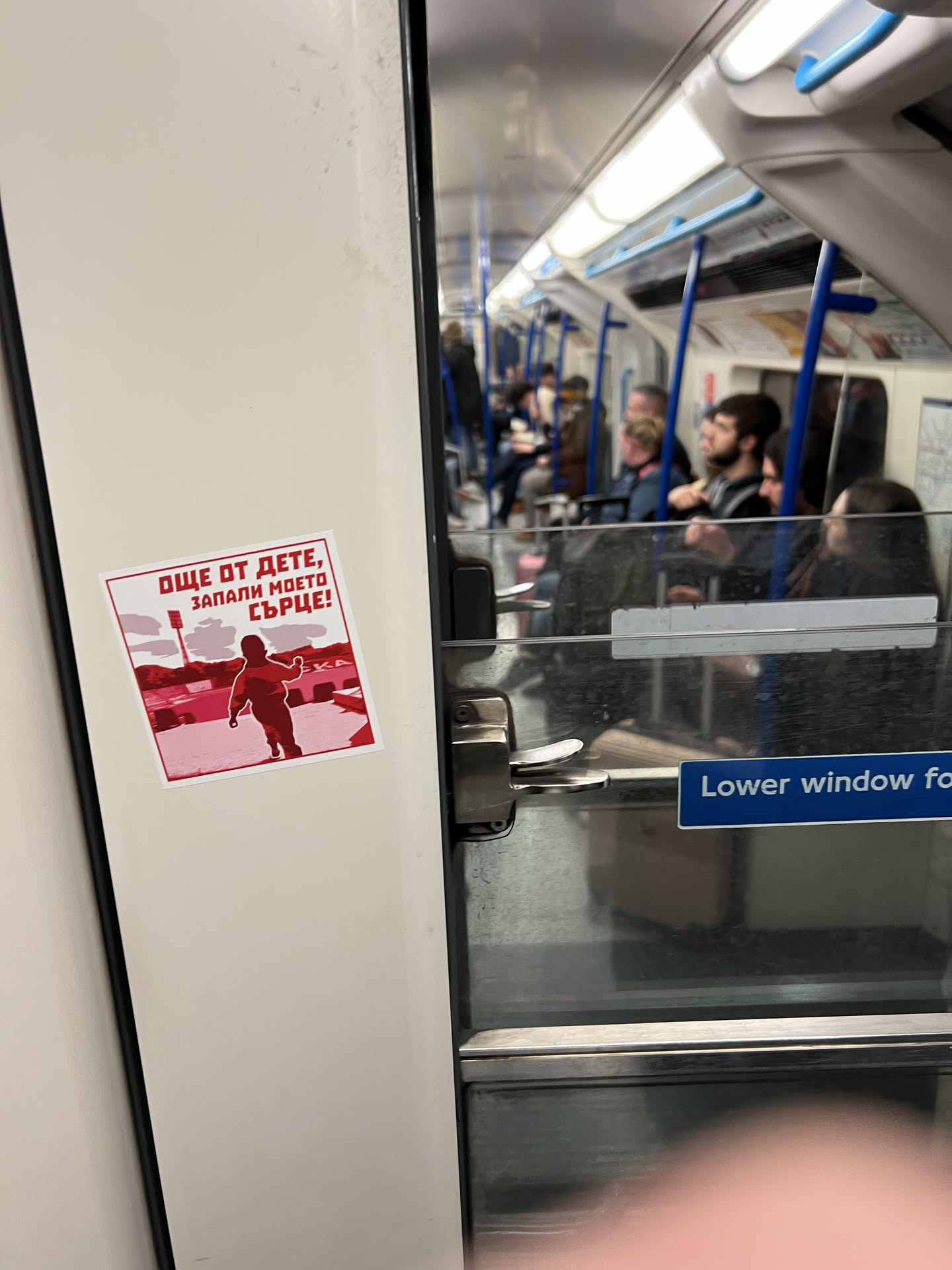 A square sticker with a white border, predominantly featuring a two-tone red and white color scheme. The background is a lighter, faded red, depicting what appears to be a stadium or arena with floodlights. In the foreground, a dark red silhouette of a small child, seen from behind, runs towards the right. Above the child, there's a red banner with white Cyrillic text.