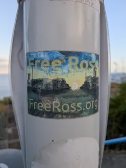 A rectangular sticker depicting an impressionistic painting of a deer in a field before stone ruins under a sunset sky. A white Bitcoin symbol glows in the center. The text 'Free Ross' and 'FreeRoss.org' frames the image in yellow lettering.