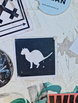 Street sticker A black and white sticker featuring a cat urinating. The cat is depicted in a simple, graphic style, and the overall tone of the sticker is slightly humorous or satirical.