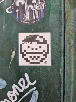 Street sticker A small square sticker with a pixel art face. The face is simple and has a happy expression. The sticker is white with black pixels. There is a copyright symbol in the bottom right corner.
