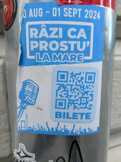Street sticker A blue and white sticker promotes an event named 'Razi Ca Prostu' La Mare' (Laugh Like an Idiot by the Sea), scheduled from August 10 to September 1, 2024. The sticker features an illustration of a microphone, a stage, and a crowd of cheering people, along with a QR code and the word 'BILETE' (Tickets).