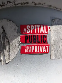 Street sticker Three red adhesive strips stacked vertically on a grey metal surface. Features bold white and black text in Romanian, partially cut off on the right side, with a small white logo.