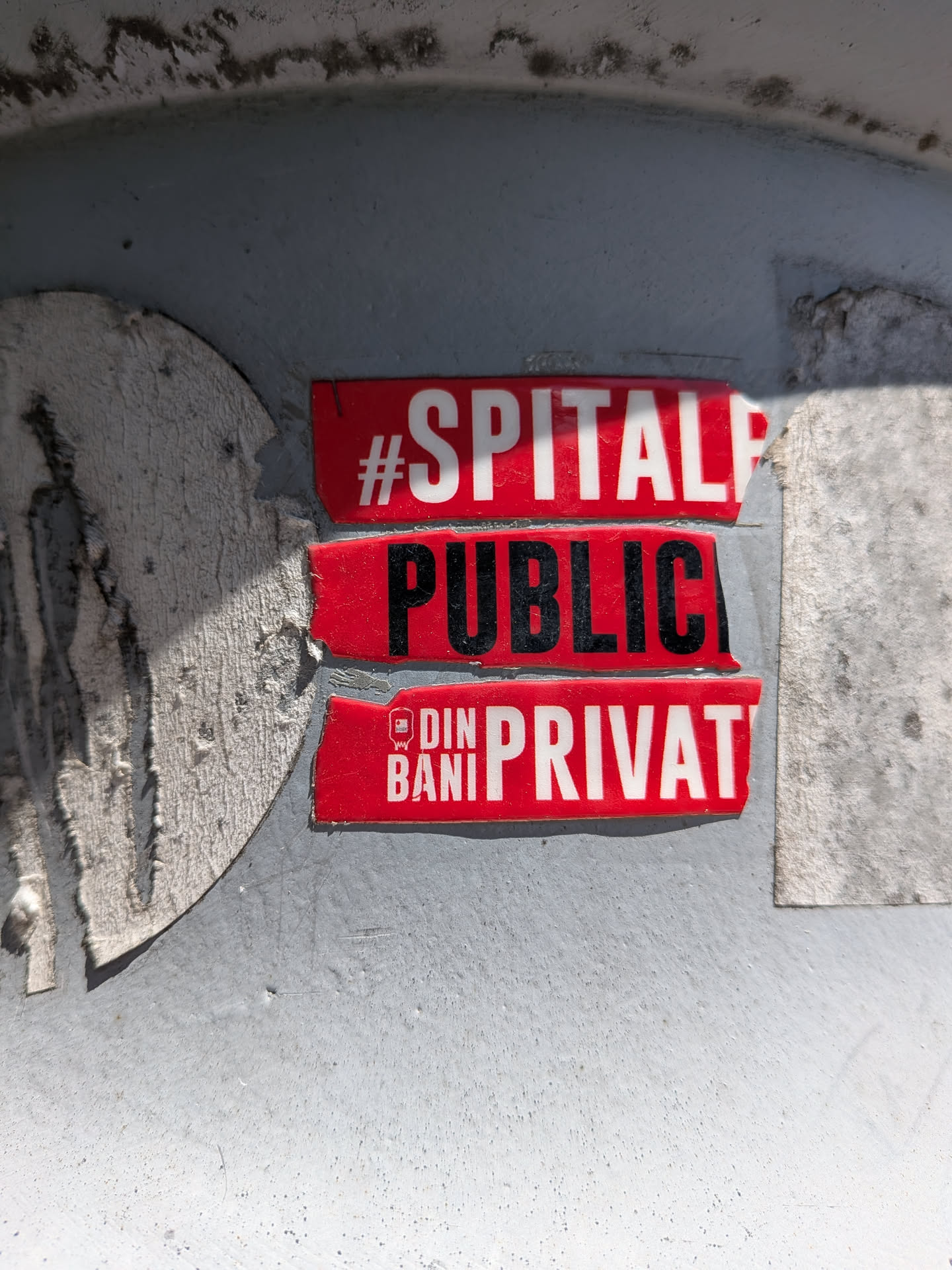 Three red adhesive strips stacked vertically on a grey metal surface. Features bold white and black text in Romanian, partially cut off on the right side, with a small white logo.