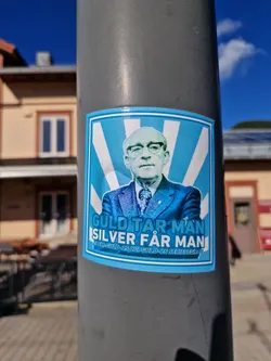 Street sticker A sticker featuring a portrait of a man with text overlayed. The text translates to "Gold you take, silver you get".  The smaller text at the bottom seems to be referencing a cup gold or series win.