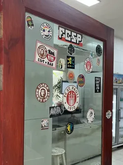 Street sticker The sticker is circular with a prominent brown outer ring. The main body of the sticker is white, featuring a stylized red building, which appears to be a fortress or a stadium gate, in the center. Above the building, 'FC ST. PAULI' is written in a bold, sans-serif font, also in red. Below the building, the year '1910' is displayed in the same red font. There are also two small red stars on either side of the building, within the white area. The overall color scheme is red, white, and brown.