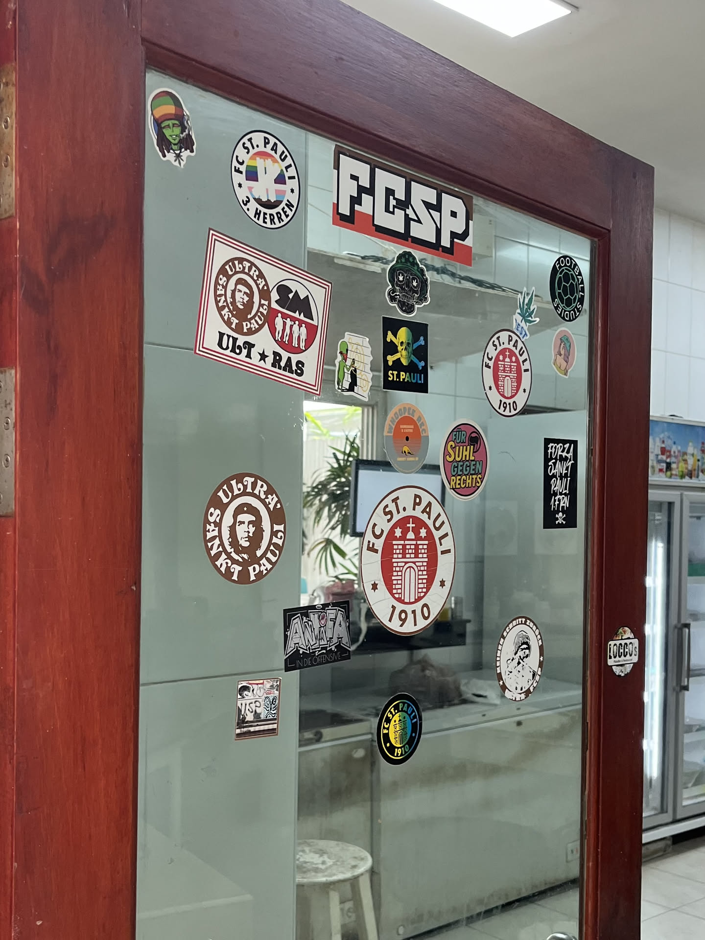 The sticker is circular with a prominent brown outer ring. The main body of the sticker is white, featuring a stylized red building, which appears to be a fortress or a stadium gate, in the center. Above the building, 'FC ST. PAULI' is written in a bold, sans-serif font, also in red. Below the building, the year '1910' is displayed in the same red font. There are also two small red stars on either side of the building, within the white area. The overall color scheme is red, white, and brown.