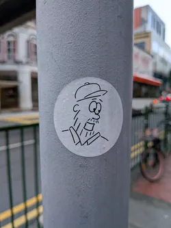 Street sticker A circular white sticker featuring a simple black line drawing of a bearded man wearing a baseball cap and a collared shirt.