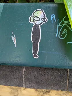 Die-cut sticker of a minimalist figure. Features a solid black body and a head filled with colorful, abstract graffiti scribbles. Outlined in white on a green background.