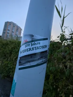 Street sticker A rectangular sticker featuring a black-and-white historical photo of stadium stands. It includes green accent borders, a red 'Energie' logo, and the bold text '100 Jahre WESERSTADION' in a gothic-style font.