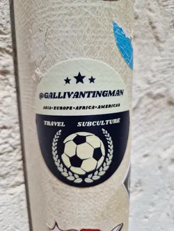 Street sticker Round sticker with a soccer ball in the center, surrounded by a laurel wreath.  Text on the sticker includes '@GallivantingMan', 'Asia Europe Africa Americas', 'Travel', and 'Subculture'. Three stars are present above the main text.