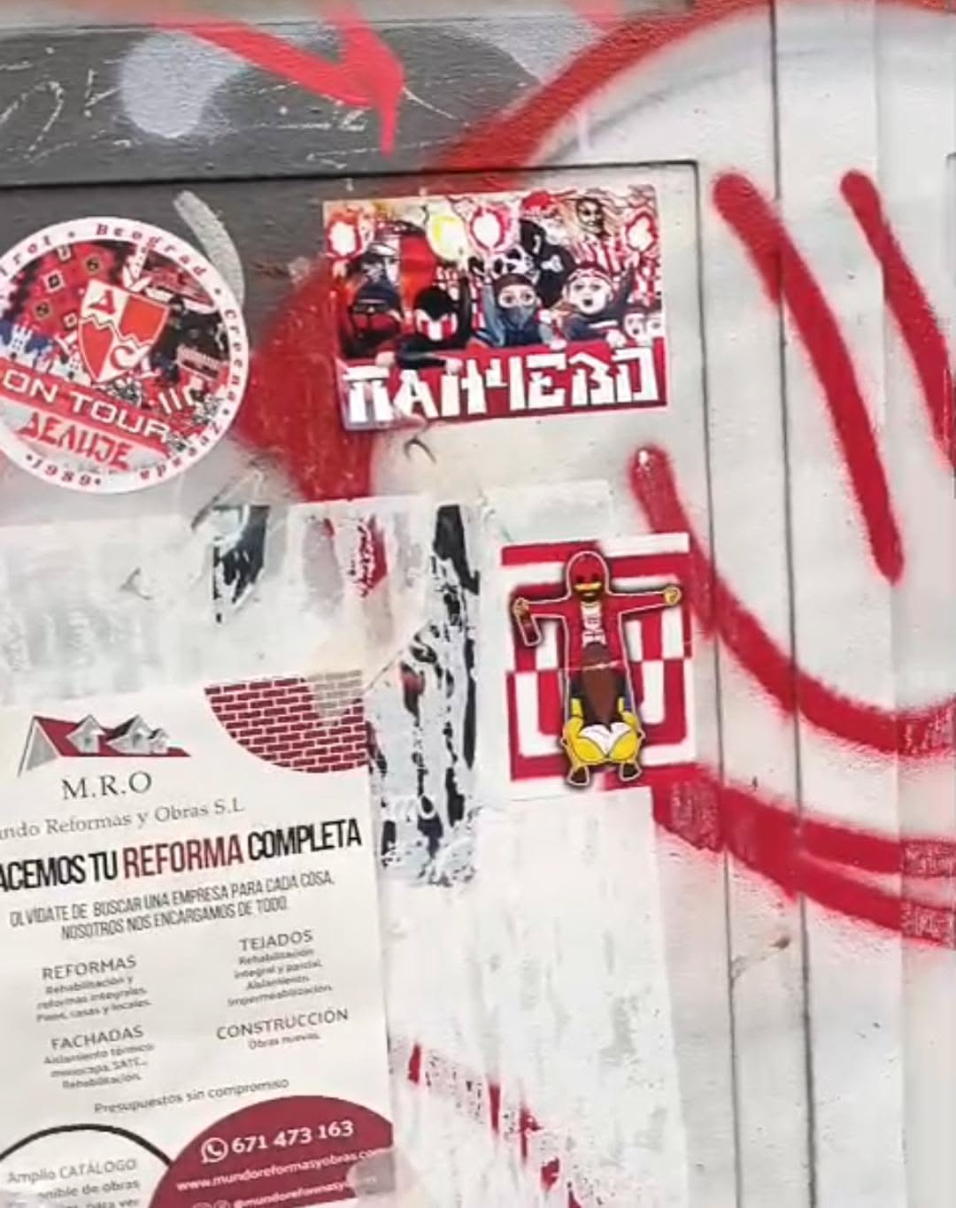 The central sticker is rectangular, featuring a dense, stylized illustration of a crowd of figures. Many figures have their faces obscured by masks, scarves, or hoods, and some appear to be holding flags or banners. The dominant colors are red, white, and black, with some yellow accents. Below the crowd, in a bold, blocky white font with a red outline, is the Cyrillic word 'ПАНЧЕВО'. The overall appearance conveys a sense of unity, intensity, and group identity.