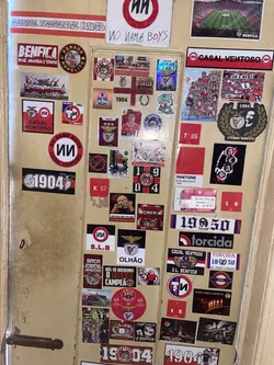 Street sticker The sticker is circular, featuring a bold design with a red outer ring and a white inner circle. The top arc of the white circle displays the text 'NO NAME BOYS' in a strong, black, slightly stylized font. The bottom arc of the white circle reads 'CASAL VENTOSO' in a similar black font. Centered within the white circle is a distinctive stylized 'UU' symbol, also in black. The overall appearance is clean yet impactful, with the red, white, and black colors creating a striking contrast. The sticker shows minor signs of wear, consistent with a physical adhesive item.