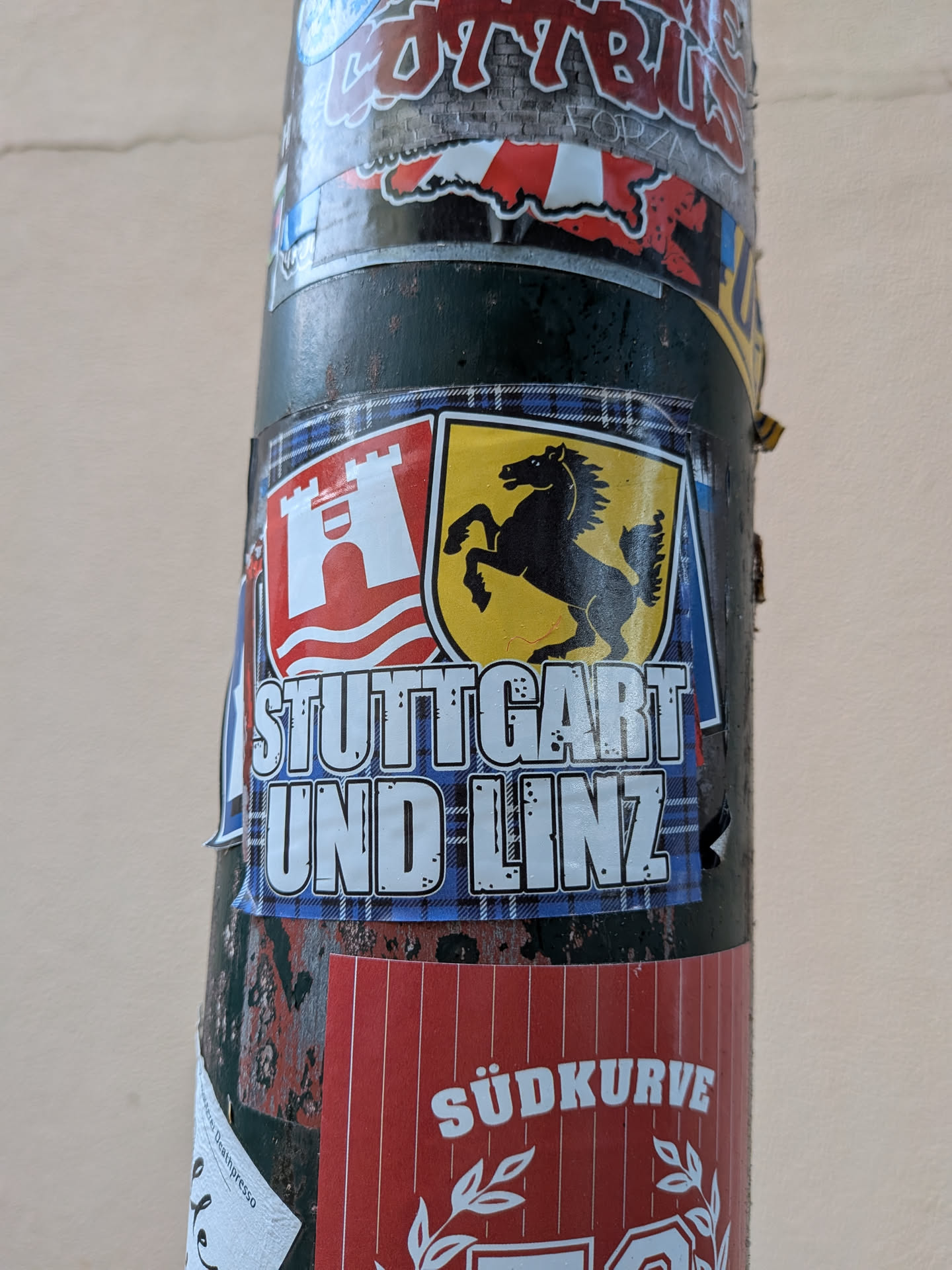 Rectangular sticker with a blue tartan background. Features the coats of arms of Linz (red shield, white castle) and Stuttgart (yellow shield, black horse) above the bold white text 'STUTTGART UND LINZ'.