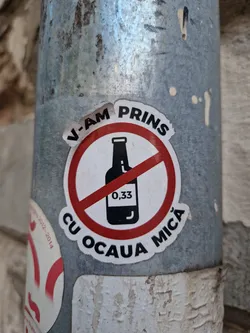 Street sticker A sticker depicting a bottle with a red circle and line through it, with text in Romanian. It translates to "I caught you red-handed!" and likely refers to catching someone drinking alcohol illegally or underage.