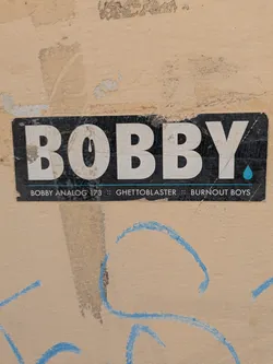 Street sticker This sticker features the name "Bobby." in white letters on a black background, followed by the text: "Bobby Analog 173 :: Ghetto Blaster :: Burnout Boys".