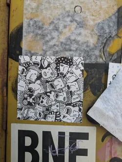 Street sticker A black and white sticker features a densely packed illustration of faces with varying expressions and styles. The faces are drawn in a doodle-like manner with thick black lines, creating a playful and chaotic composition. The white background is completely filled with the illustration.