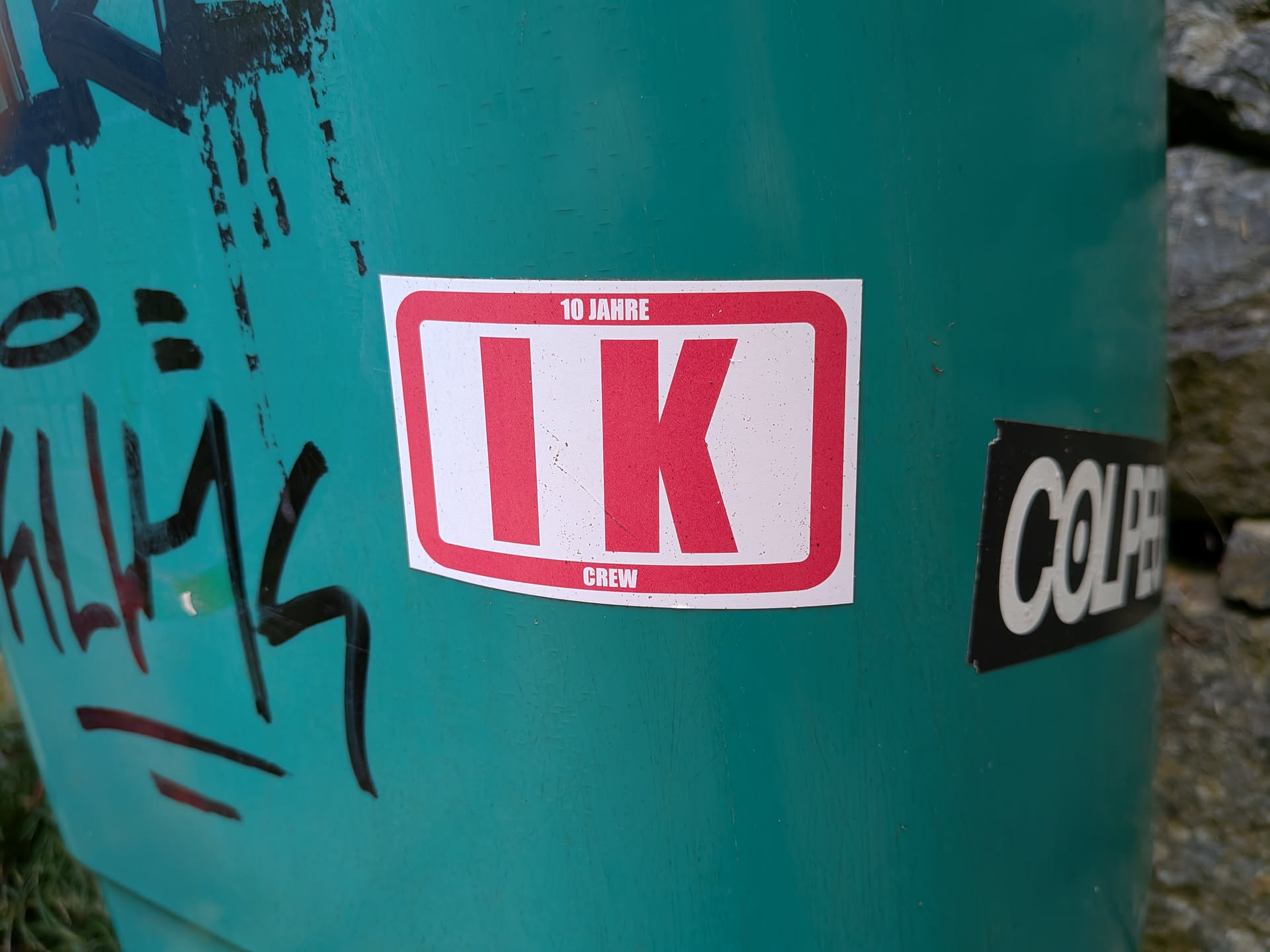 A rectangular white sticker featuring a thick red border. Large red letters 'IK' sit in the center, with '10 JAHRE' printed on the top border and 'CREW' on the bottom.