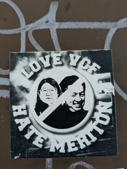 Street sticker A black and white square sticker features a circular design. Inside the circle are the faces of a woman with glasses and a man smiling, divided by a line with a line through it. Surrounding the circle is the text 'LOVE VCF HATE MERITOCRATION'.