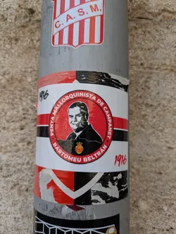 Street sticker The sticker is a circular design with a portrait of Bartomeu Beltrán in the center, surrounded by a red and white band.  The text around the circle reads "PENYA MALLORQUINISTA DE CAMPANET • BARTOMEU BELTRÁN". The sticker also displays the year 1916 in two different places.
