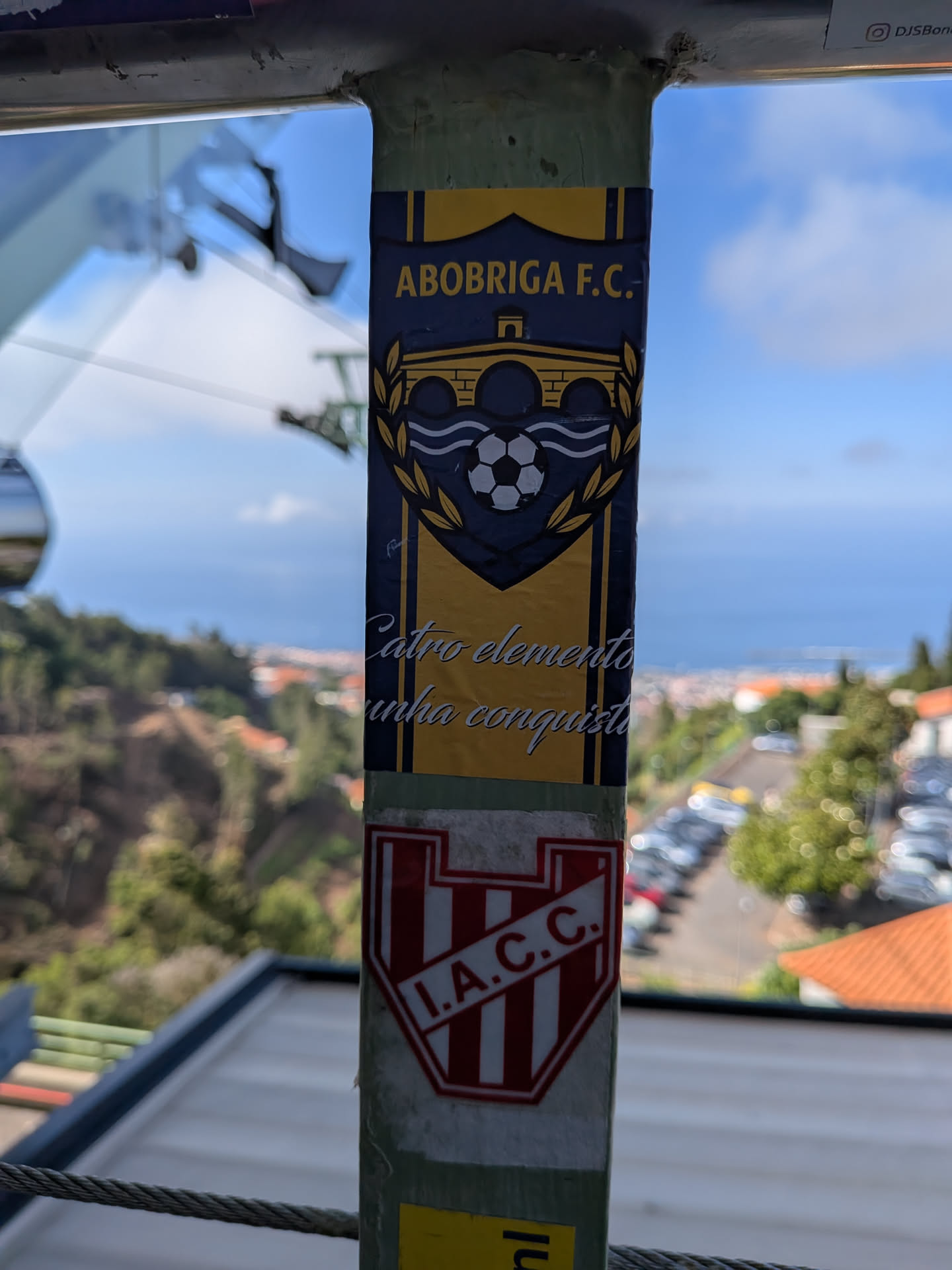 A vertical rectangular sticker with a yellow and dark blue color scheme. It features a central crest with a bridge, waves, a soccer ball, and a laurel wreath. Text at the top reads 'ABOBRIGA F.C.' and cursive text at the bottom reads 'Catro elementos unha conquista'.