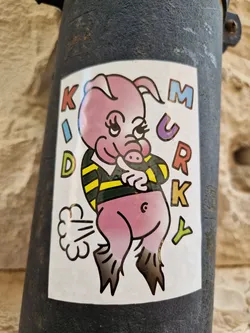 Street sticker A sticker featuring a cartoon pig in a rugby shirt, farting. The words "KID MURKY" are written vertically on either side of the pig.