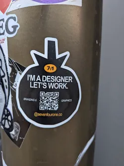 Street sticker A black, bomb-shaped sticker with a white border. It displays promotional text, a QR code, and a social media handle in yellow.