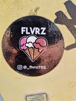 Round sticker with a black background featuring the word FLVRZ in white sans-serif font, and three ice cream cones with pink, white, and red ice cream scoops.  There is an Instagram handle below the main design.