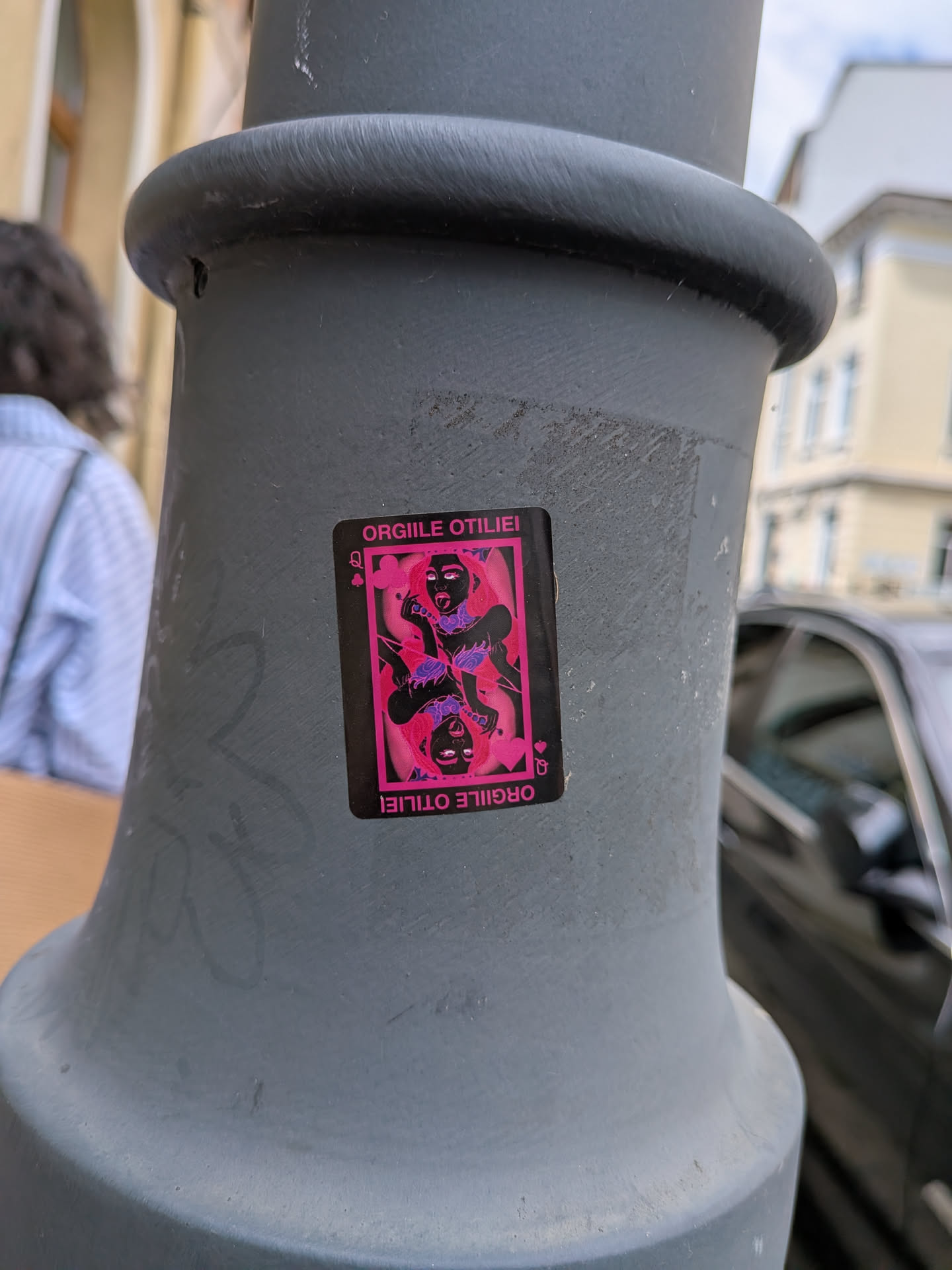 A rectangular black sticker designed to look like a Queen playing card. It features a symmetrical, double-headed illustration of a woman with pink hair, dark skin, and purple accents. The Romanian text 'ORGILE OTILIEI' is printed in pink at the top and bottom.